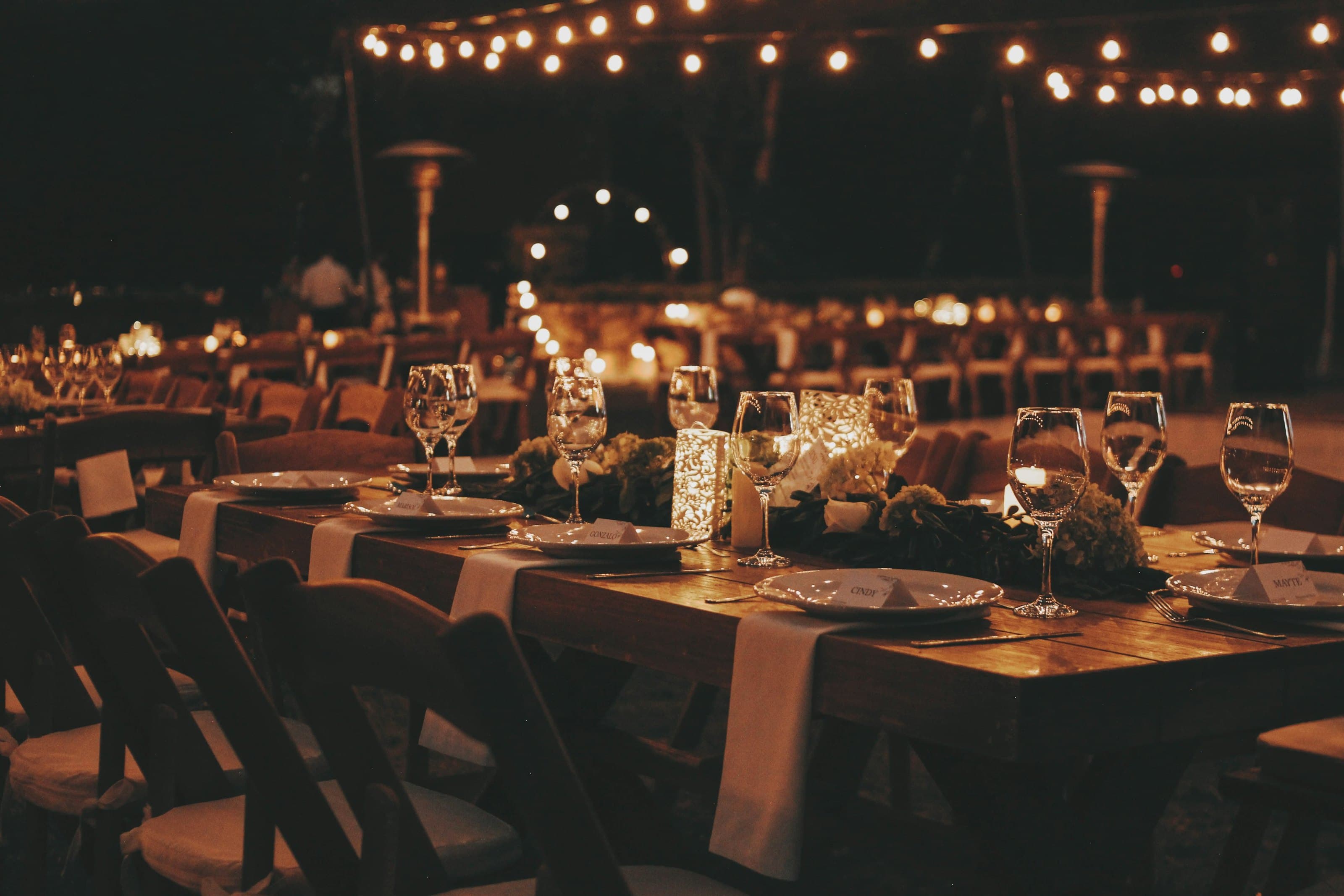 An evening table laid with glassware and candles under warm lights