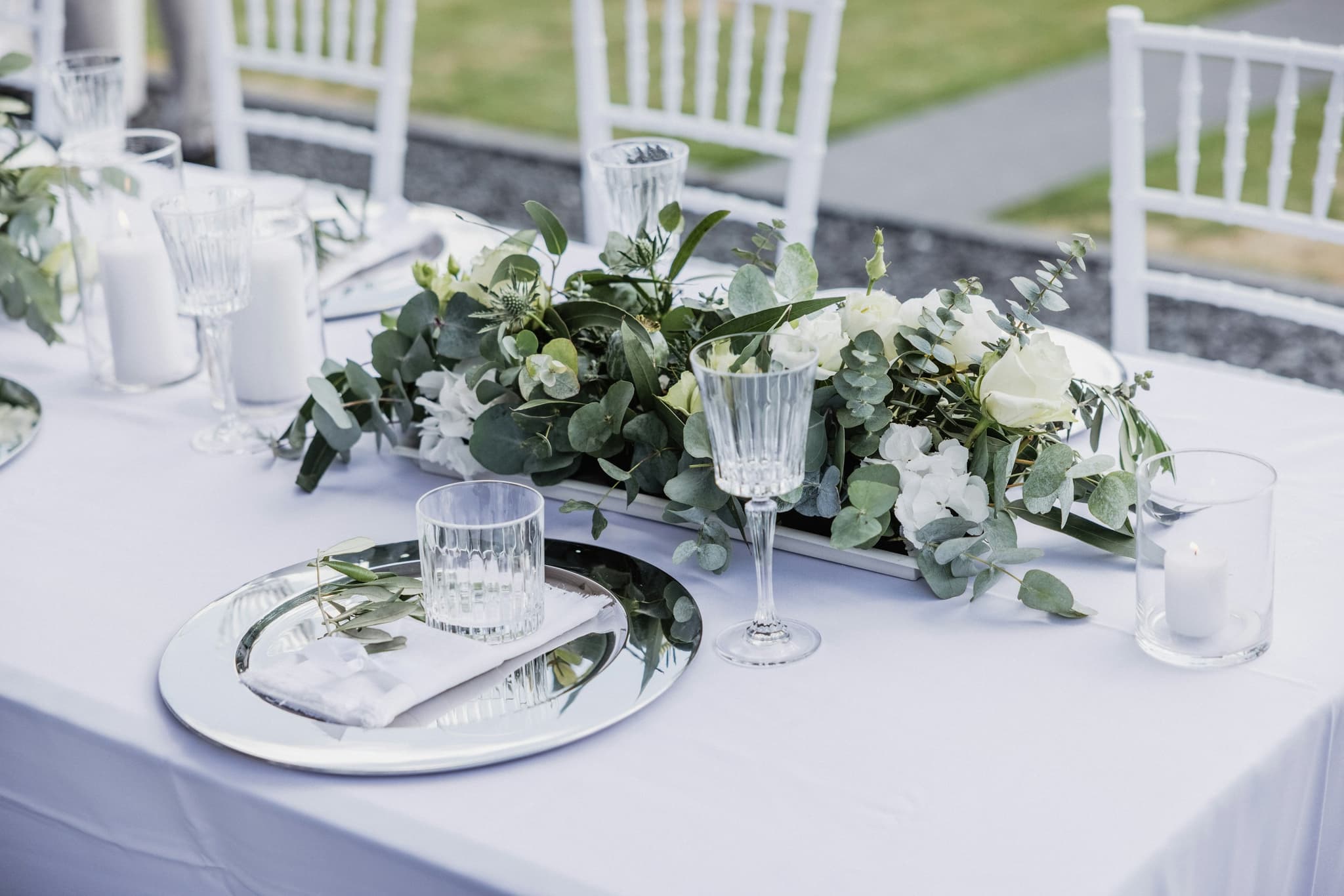 A table laid with white flowers, greenery and crystal glassware