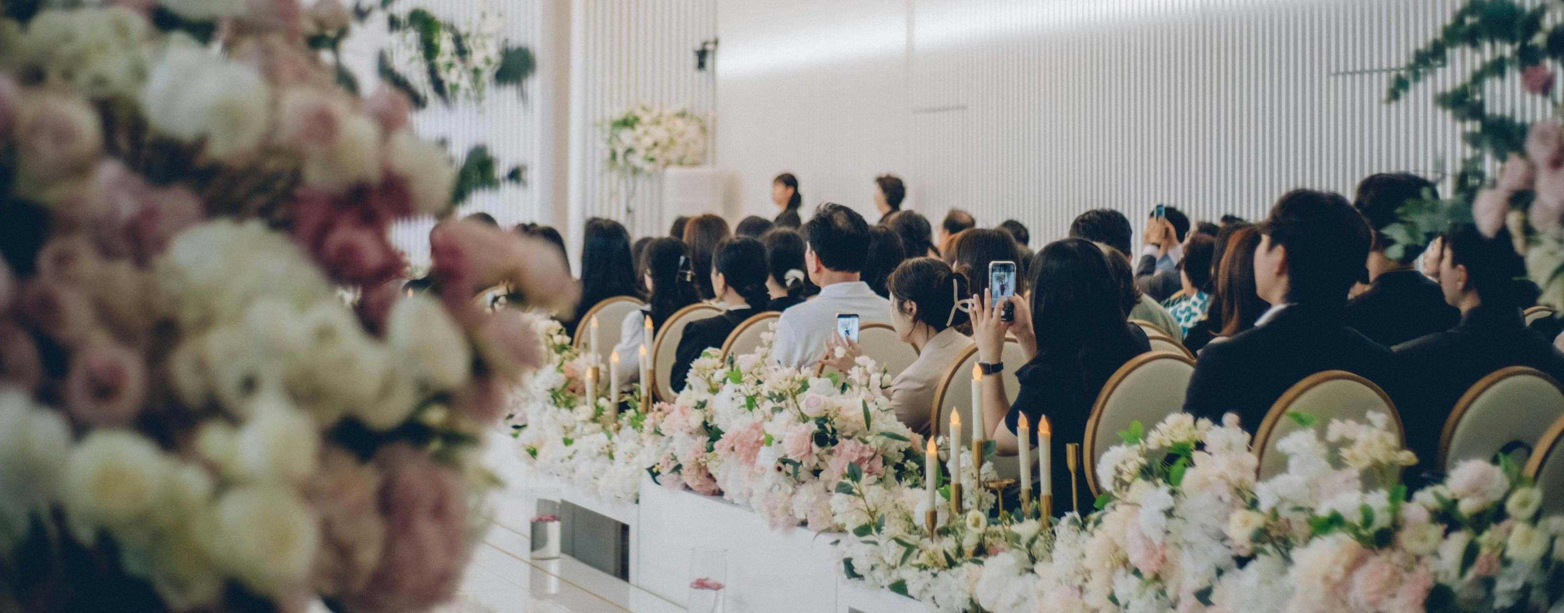 Seated guests framed by tall floral arrangements