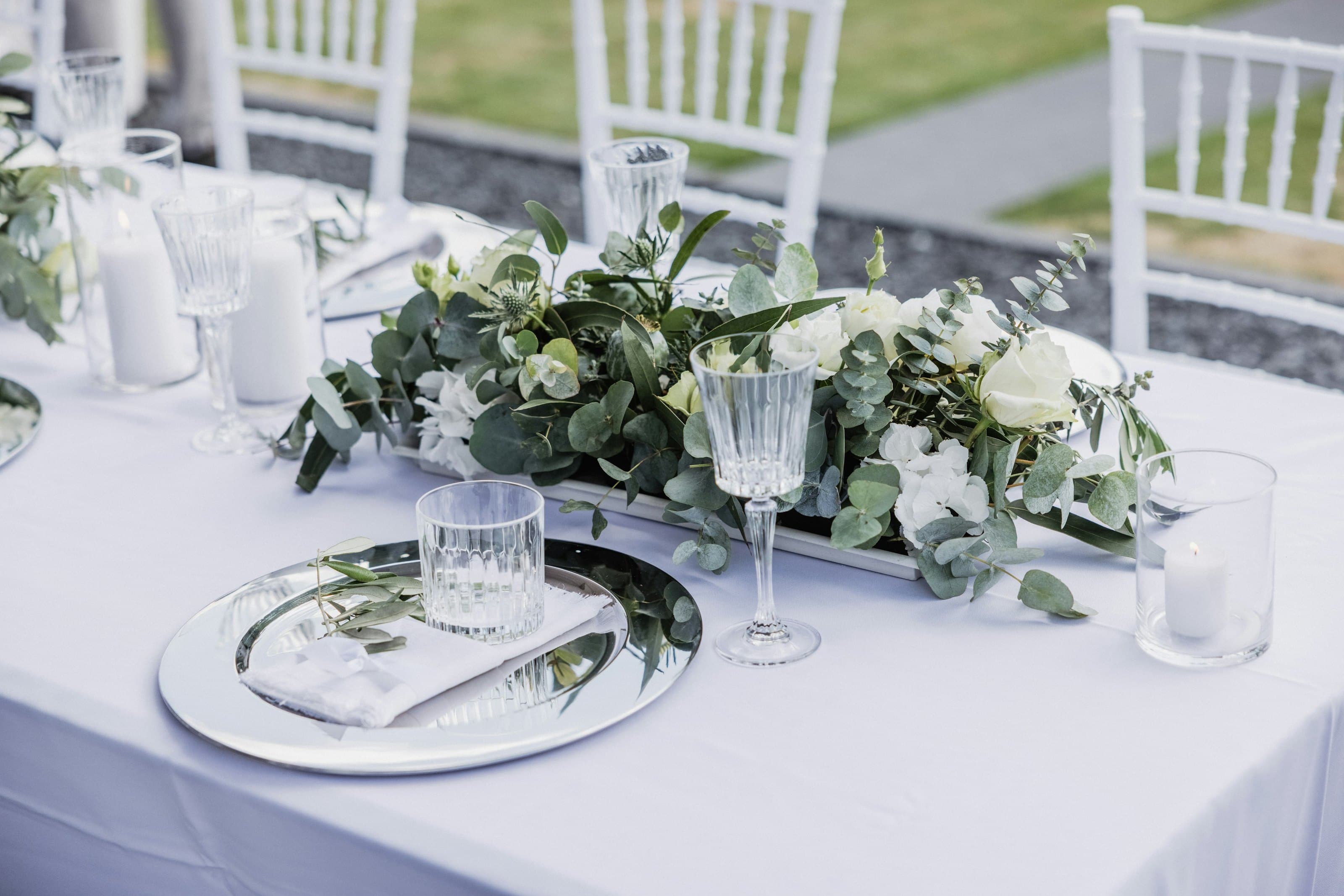 A table laid with white flowers, greenery and crystal glassware