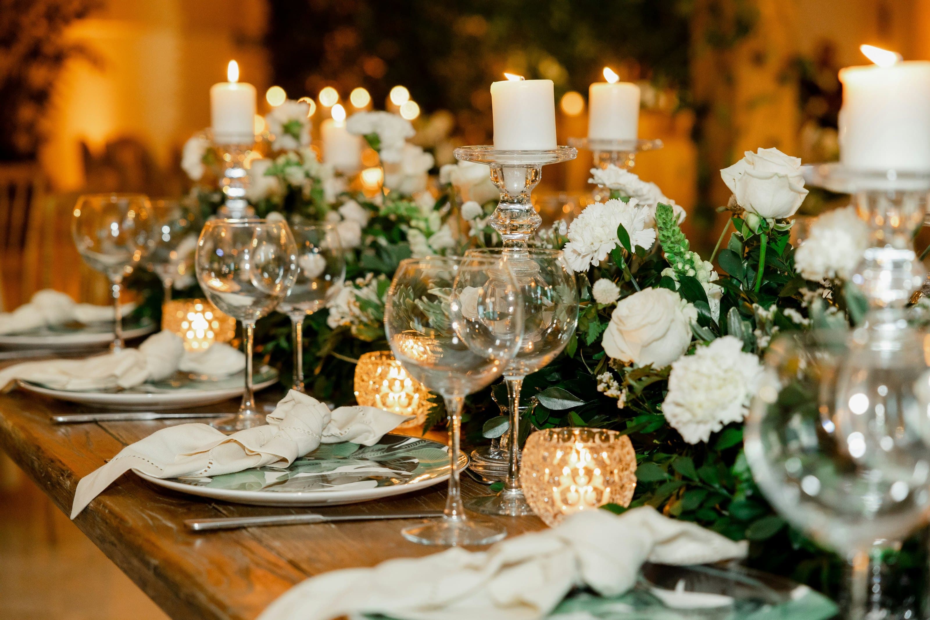Close view of a table setting with white roses, crystal glasses and candlelight